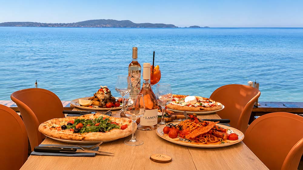 Gaetano Plage — Restaurant Italien sur la plage de l'Almanarre à Hyères Table vue mer au restaurant Gaetano Plage sur la plage de l'Almanarre à Hyères avec pizzas et rosé