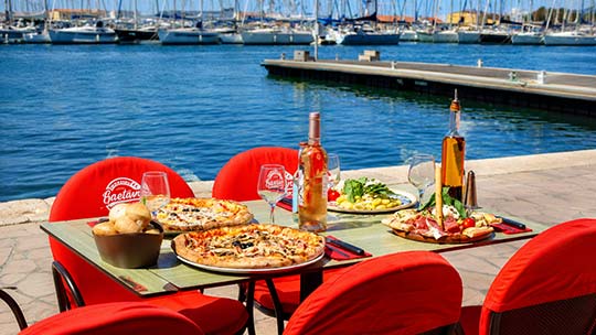 Pizzeria Gaetano Toulon Port — Terrasse face à la mer Table en terrasse de la Pizzeria Gaetano au port de Toulon avec pizzas et vue sur la marina