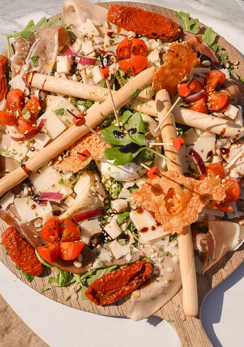 Gaetano Plage — Entrées et salades italiennes sur la plage de l'Almanarre à Hyères Entrée italienne généreuse avec salade, gressins, tomates séchées et mozzarella au restaurant Gaetano Plage l'Almanarre à Hyères